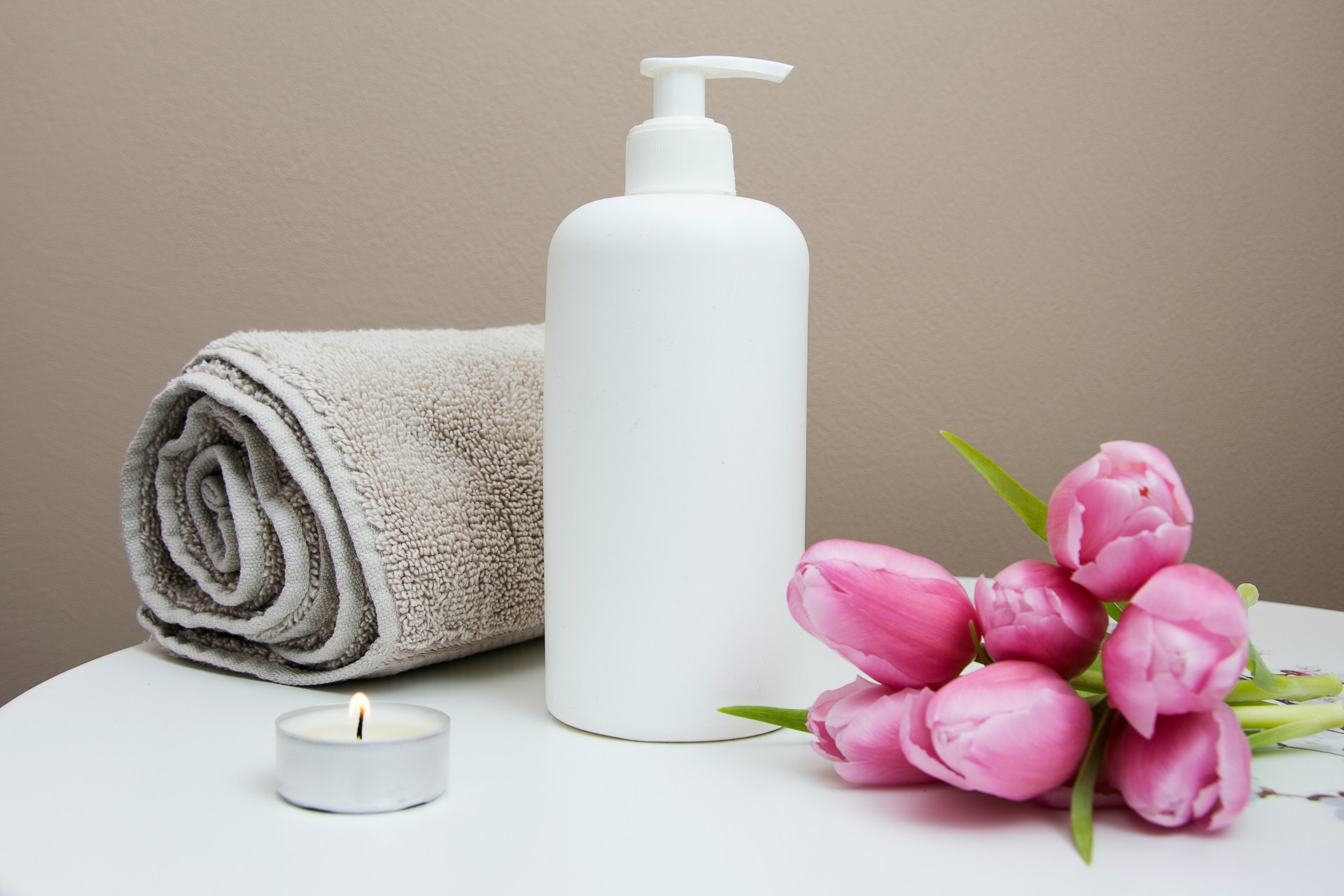 Cream pump with a rolled towel, tea-light candle and roses